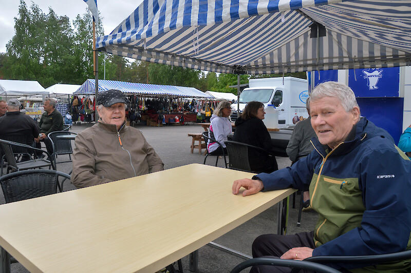 Kaksi miestä torilla istumassa pöydän ääressä