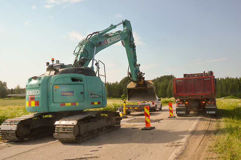 Tietöitä kaivinkone ja kuorma-auto tiellä